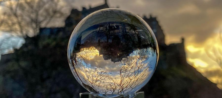 Image of glass ball in front of Edinburgh Castle which sits in the background as the sun sets